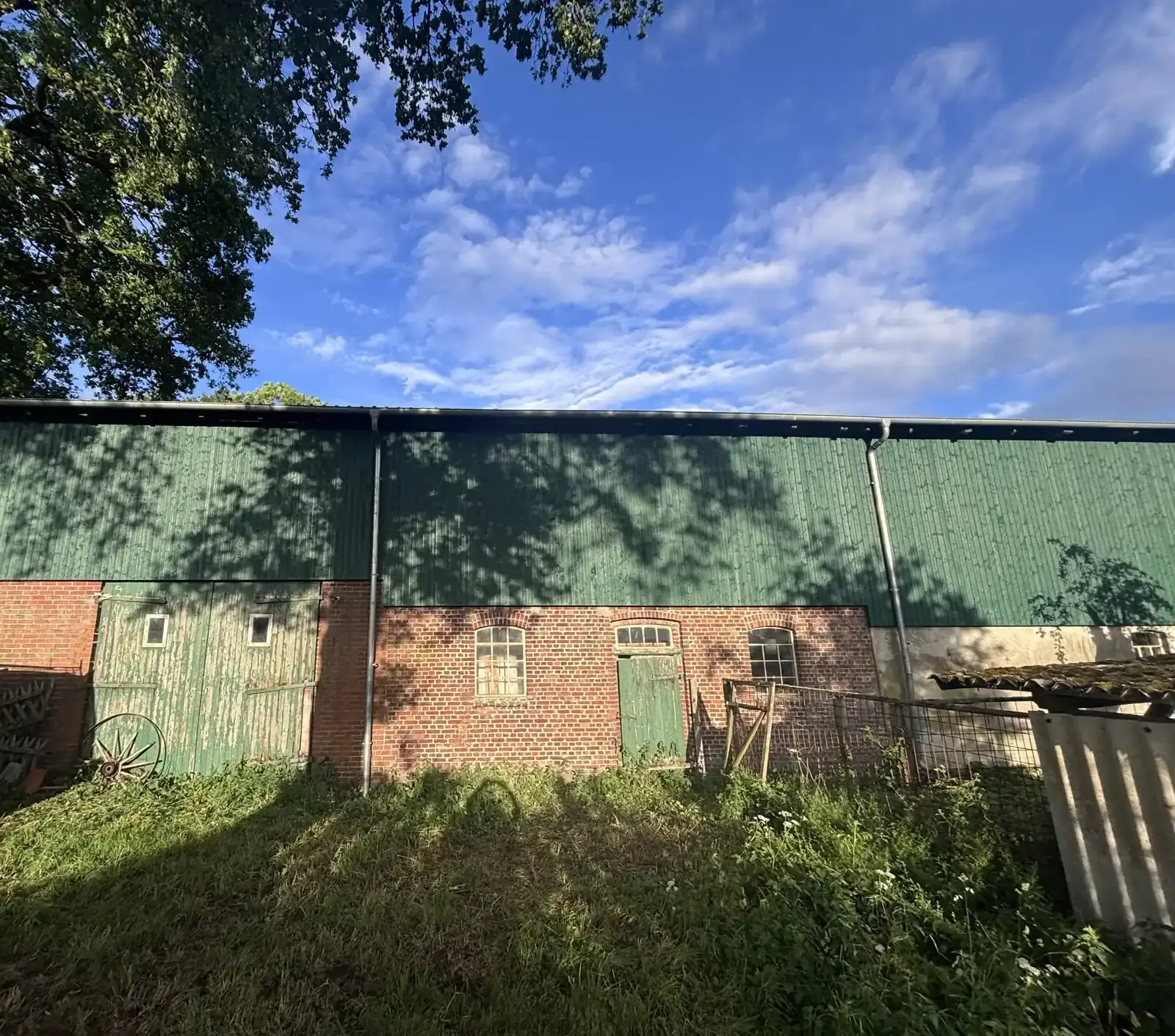 Scheunenfassade mit grüner Holzverkleidung über einem Klinkersockel